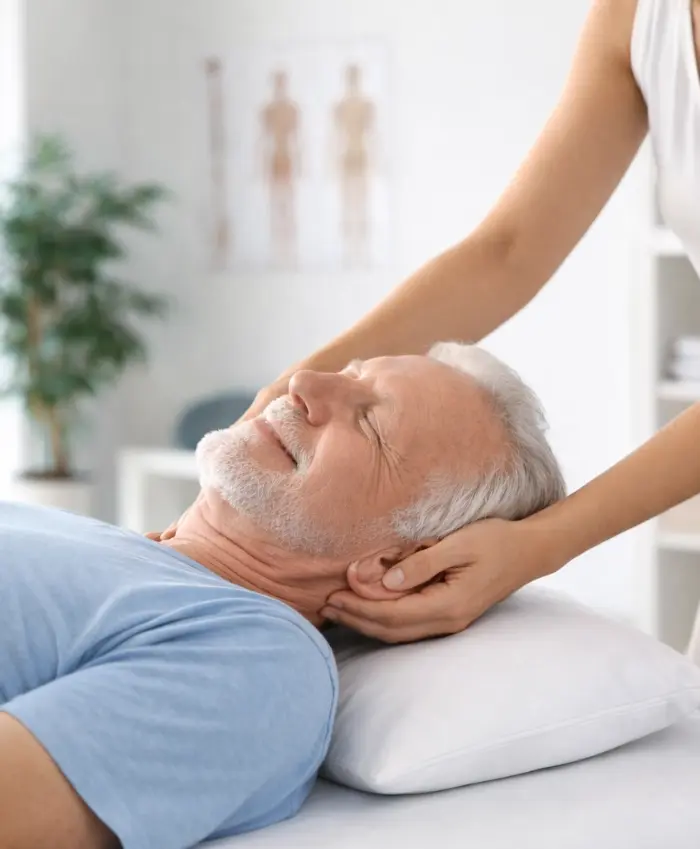 Consultation d'ostéopathie pour un patient senior, travail sur la mobilité du cou.