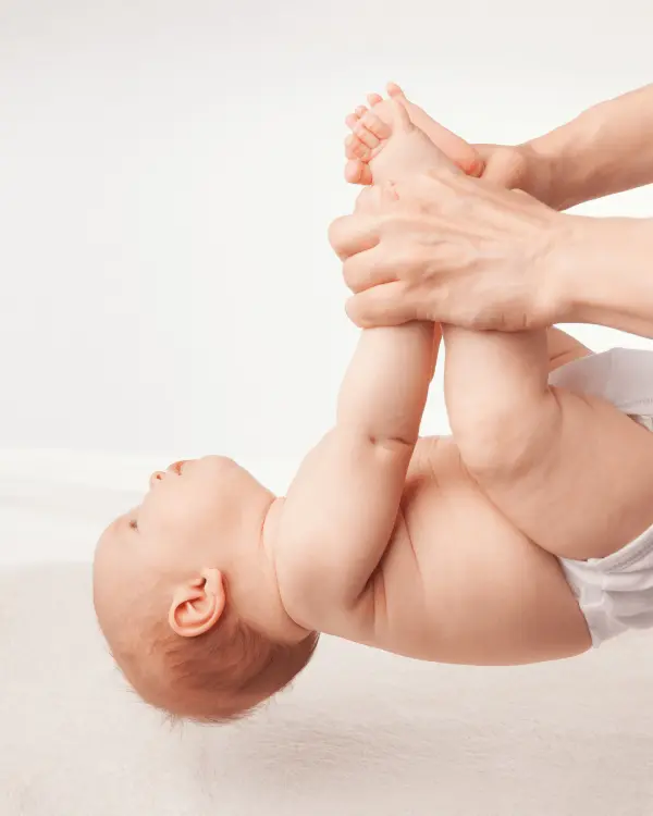 Ostéopathe manipulant avec douceur les pieds d'un nouveau-né pour un bilan pédiatrique.